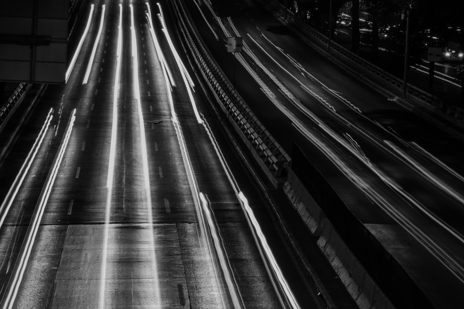 Fotografía nocturna en blanco y negro de rastros de luz sobre una avenida